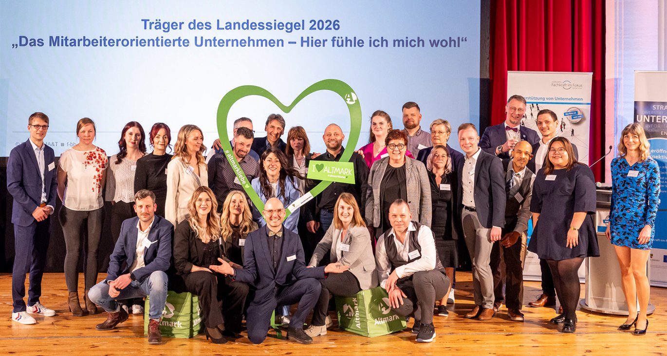 Viele Menschen stehen auf einer Bühne und jubeln, weil sie gerade eine Auszeichnung von der Arbeitsministerin des Landes Sachsen-Anhalt erhalten haben.