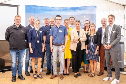 Eine Gruppe Menschen stehen auf einer Messe an ihrem Firmenstand.