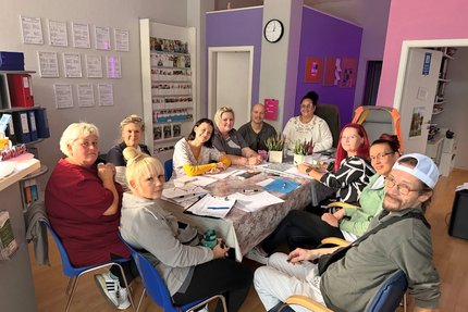 eine Gruppe Menschen sitzen an einem Tisch in einer dienstlichen Besprechung