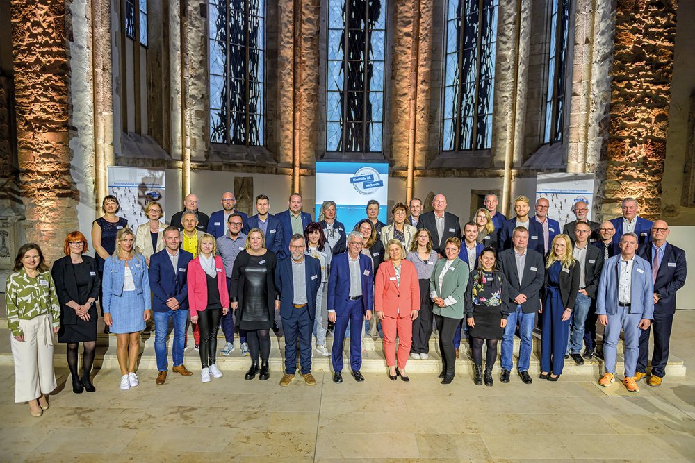 Viele MEnschen stehen auf der Bühne der Johanniskirche Magdeburg und zeigen stolz ihre Urkunden des Landessiegels.