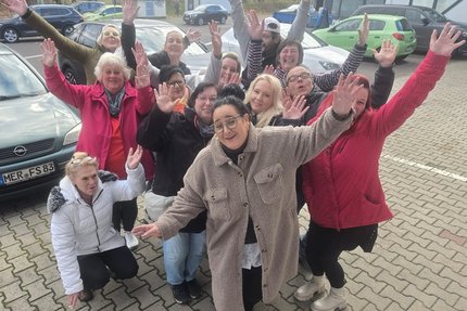 eine Gruppe Menschen stehen auf einem Parkplatz und jubeln
