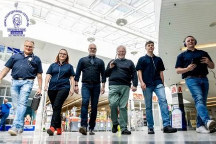 sechs Menschen laufen in einem Einkaufcenter nebeneinander