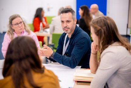 Vier Menschen sitzen am Tisch und unterhalten sich.