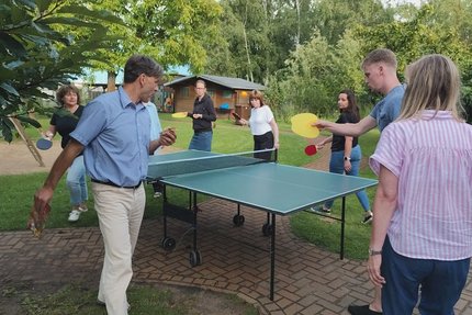 Eine Gruppe Menschen spielen im Garten Tischtennis