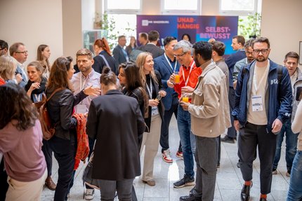 Viele Menschen stehen im einem Foyer und unterhalten sich.