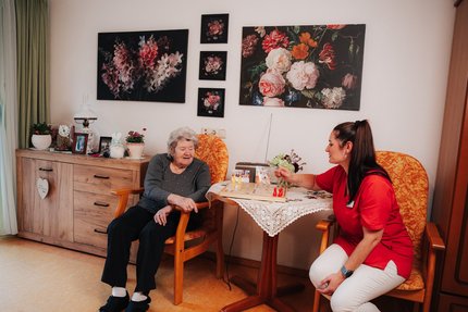 Eine alte und eine junge Frau sitzen an einem Tisch und spielen Mensch ärgere dich nicht