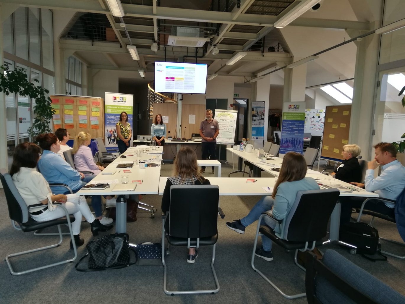 Vortragende und Zuhörende in einem Workshop-Raum