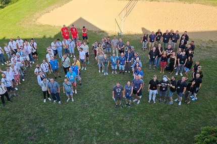 Eine Gruppe von Menschen stehen und formieren die JahresZahl 1893 auf einer Wiese.