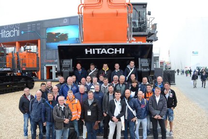 Eine Gruppe Menschen stehen vor einer meterhohen Baumaschine