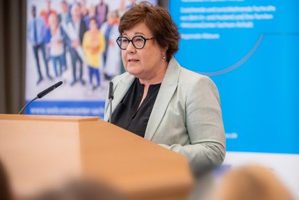 Eine Dame steht konzentriert am Rednerpult.