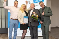 Auszeichnung mit Urkunde und Blumen beim Landessiegel „Das mitarbeiterorientierte Unternehmen – Hier fühle ich mich wohl“ in Sachsen‑Anhalt – starkes Zeichen für Arbeitgeberattraktivität und modernes Employer Branding.