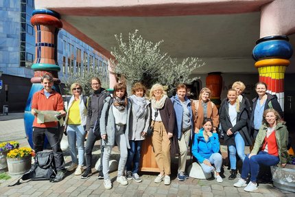 Eine Gruppe Menschen stehen vor einem Hundertwasser Haus