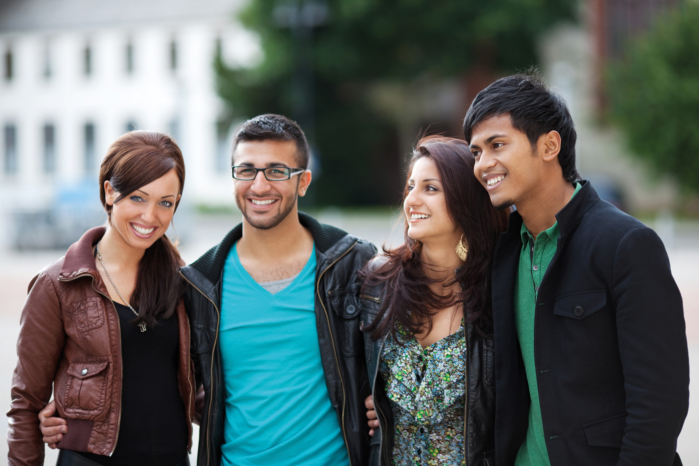Zwei junge Frauen und zwei junge Männer mit ausländischer Herkunft stehen in einer Gruppe und lächeln
