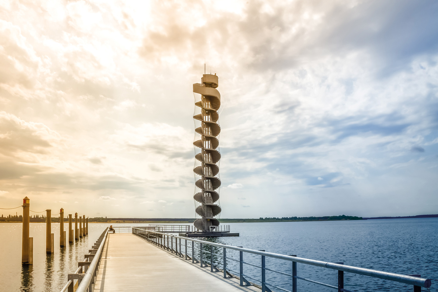 Ein Steg an einem See mit Blick auf einen Turm